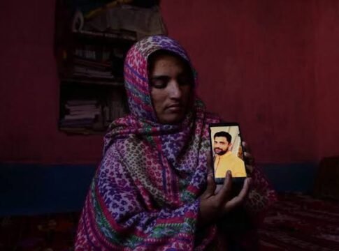 A relative holding slain Amir Ahmad Magray's picture in phone. Photograph by Mukhtar Zahoor
