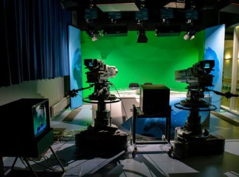A TV studio setup featuring cameras and a green screen for production purposes.