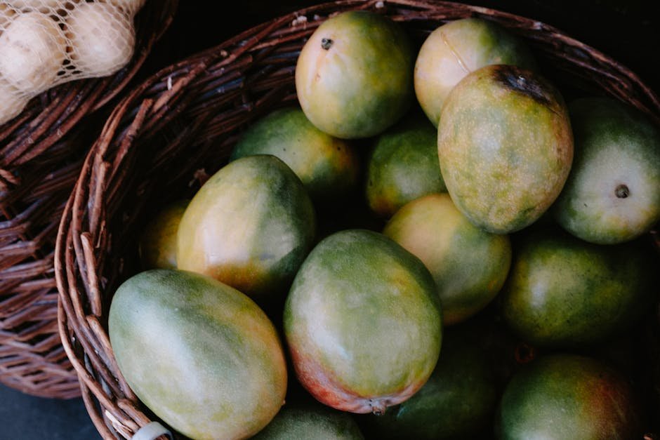Konkan Alphonso Mango Crop Faces Shortage Due to Adverse Weather Conditions A close-up view of fresh mangoes in a rustic woven basket, highlighting their natural appeal.