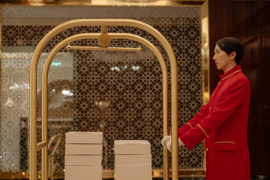 Pune Hotels Experience 20% Occupancy Decline Amid West Asia Conflict, Domestic Demand Provides Buffer A hotel bellboy in uniform pushes a luggage cart with boxes indoors, demonstrating hospitality service.