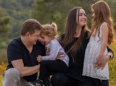 A joyful family enjoying a moment outdoors with their daughters.