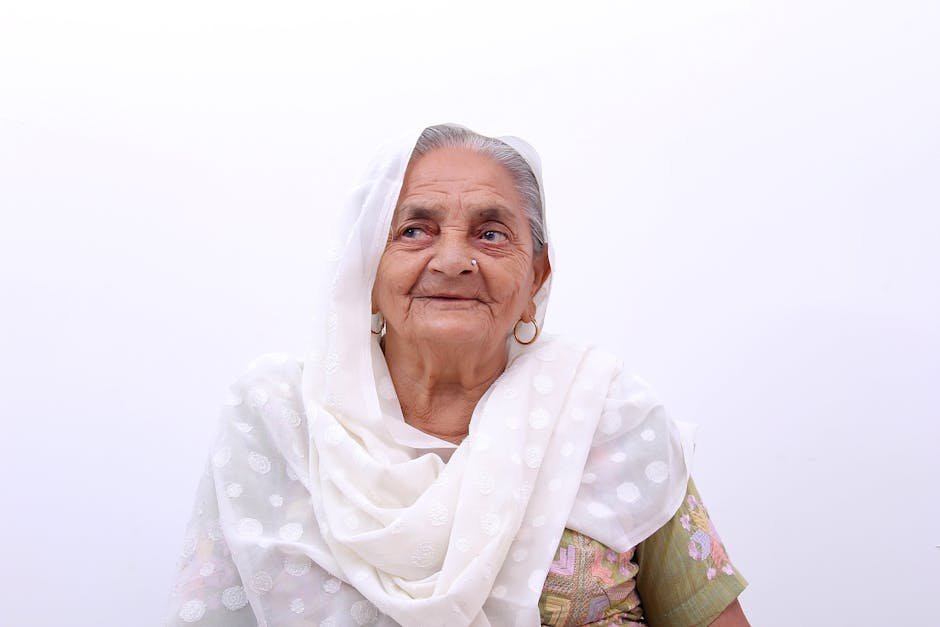 Pune Nonagenarian Undertakes Solo Journey to Pakistan to Revisit Childhood Home A joyful senior woman smiling warmly in traditional clothing against a plain background.