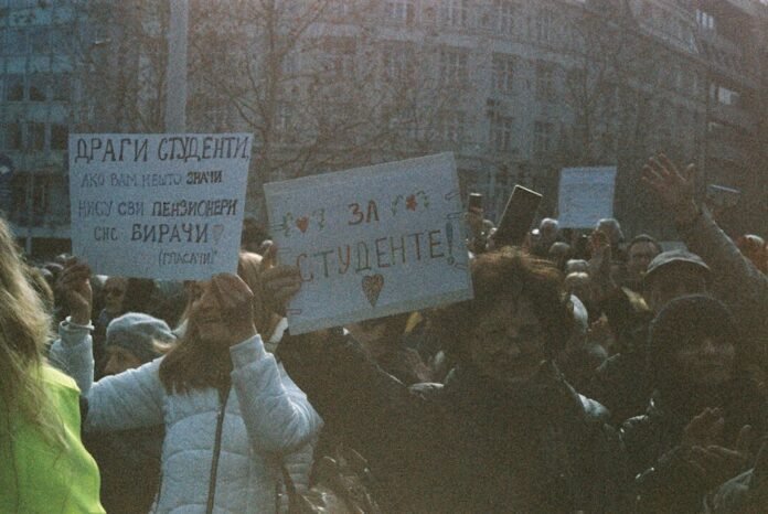 A large group of students holding signs during a peaceful protest outdoors. A large group of students holding signs during a peaceful protest outdoors.