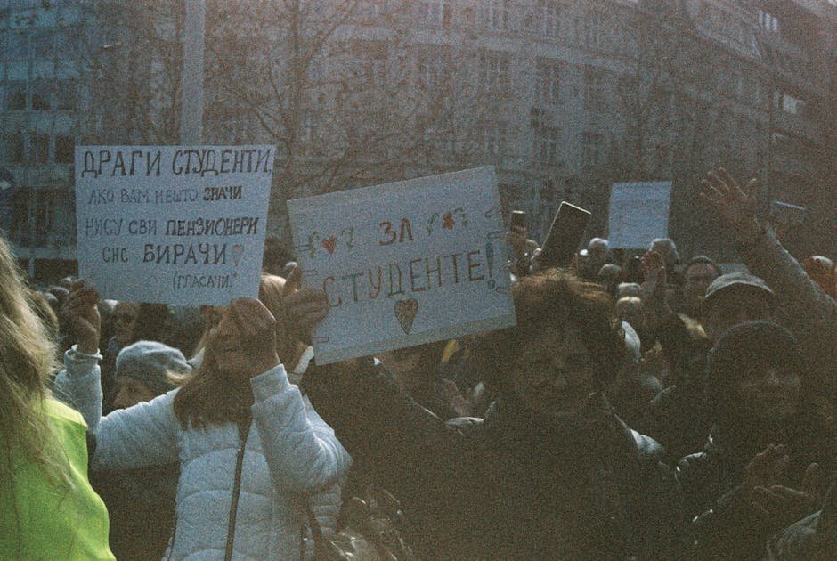 A large group of students holding signs during a peaceful protest outdoors. A large group of students holding signs during a peaceful protest outdoors.