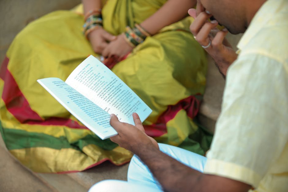 Pune Family Advocates for Preservation of Kelkar Ancestral Samadhi A man and woman in traditional attire reading a book outdoors, showcasing cultural heritage.