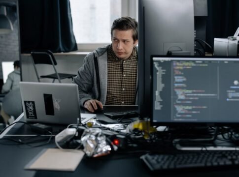 A programmer in a modern office working on computer code, showcasing a focused work environment.