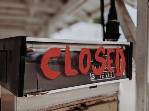 A red 'CLOSED' sign painted on an old gas pump at an outdoor station. A red 'CLOSED' sign painted on an old gas pump at an outdoor station.