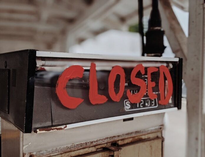 A red 'CLOSED' sign painted on an old gas pump at an outdoor station.