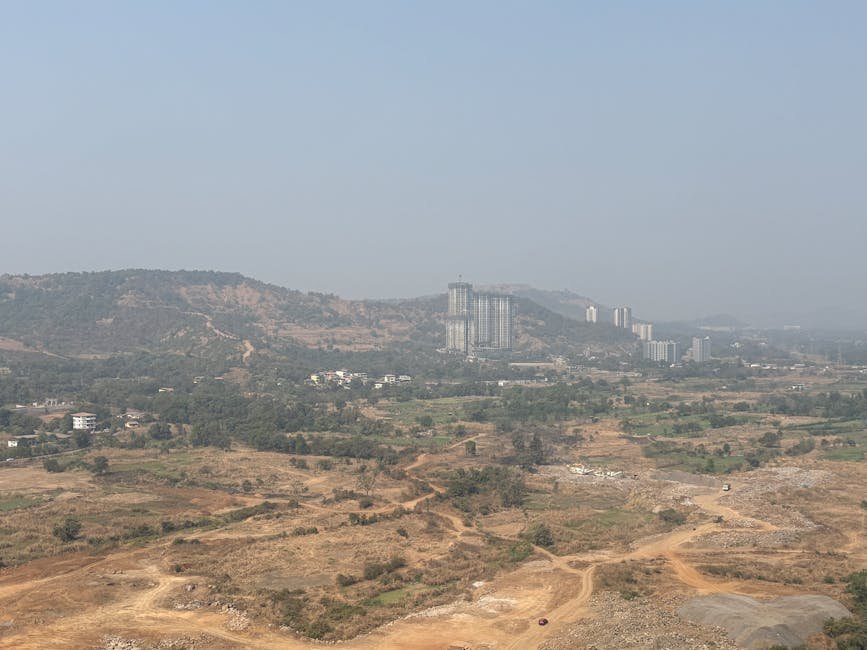 Pune Swelters as Summer Intensifies with Rising Temperatures A scenic view of Pune's countryside with hills and high-rise buildings under a clear sky.