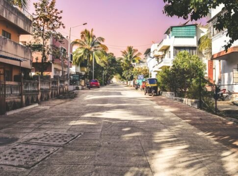 A serene neighborhood street in Pune with palm trees and parked vehicles under a warm sky. A serene neighborhood street in Pune with palm trees and parked vehicles under a warm sky.