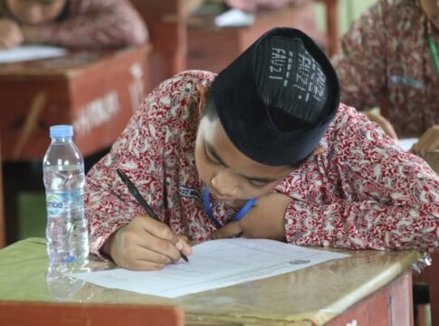 A student in traditional clothing focused on writing an exam at school.