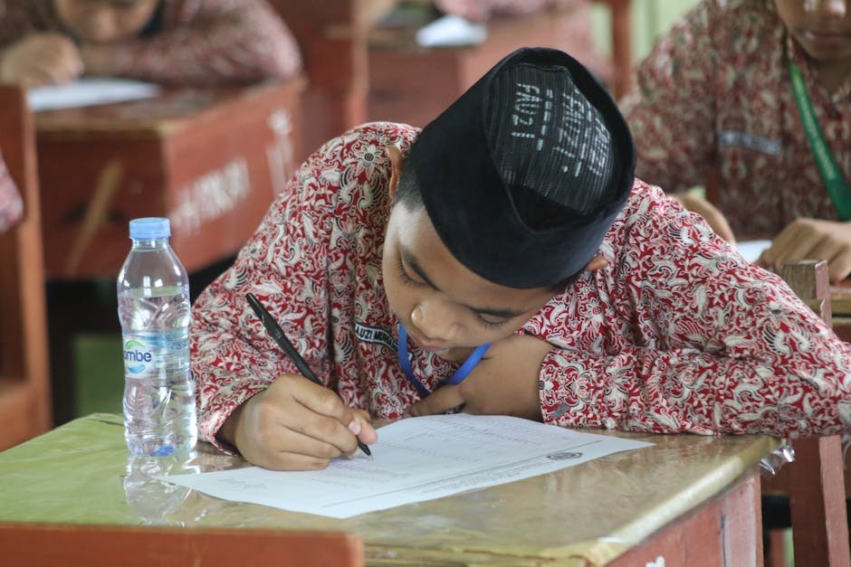 A student in traditional clothing focused on writing an exam at school.