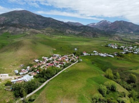 A stunning aerial view of a remote village nestled in lush green hillsides, under a bright sky. A stunning aerial view of a remote village nestled in lush green hillsides, under a bright sky.