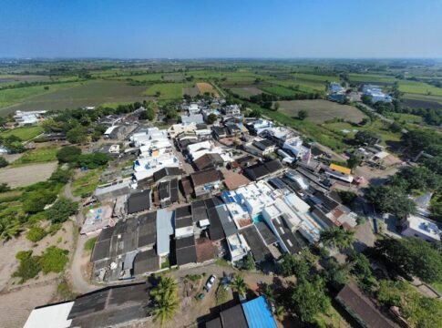 A stunning aerial view of a rural village amid lush fields in Surat, India.