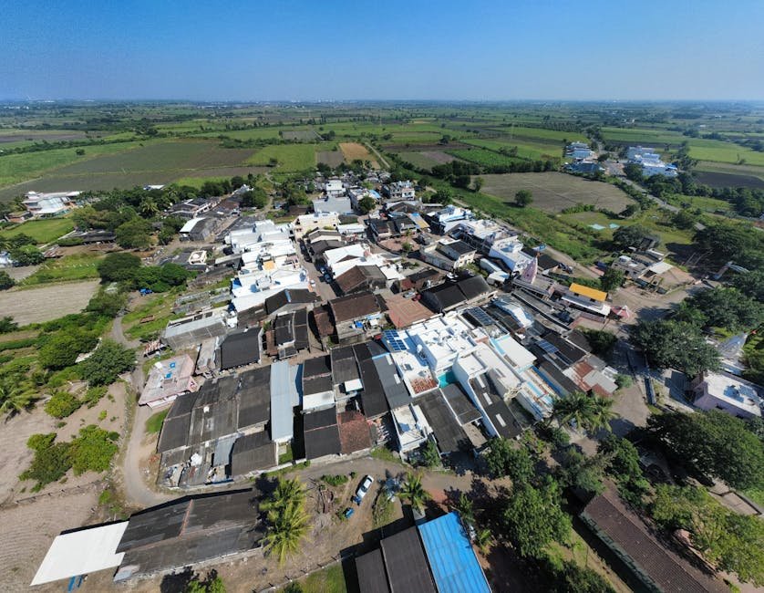 A stunning aerial view of a rural village amid lush fields in Surat, India.