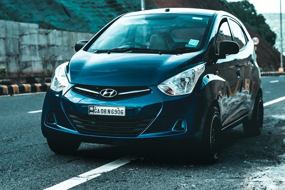 Hyundai Motor India to Increase Vehicle Prices by up to 1% From May A vibrant blue Hyundai hatchback car parked on a scenic asphalt road, perfect for travel themes.