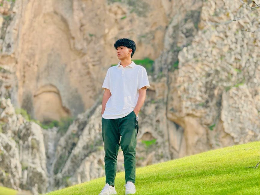UK Leads Diplomatic Push to Reopen Strait of Hormuz Amidst Global Shipping Crisis A young man in casual attire stands by a rocky cliff on a sunny day outdoors.