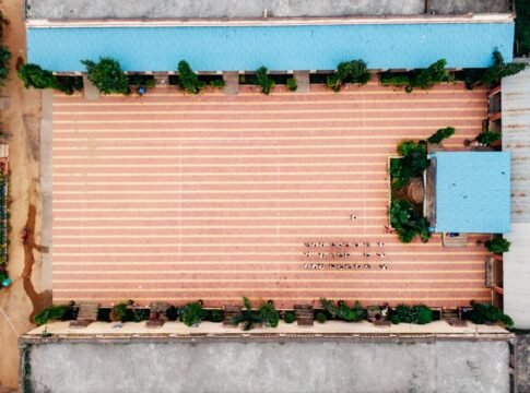 Aerial photo showcasing a large courtyard with blue roofs, greenery, and unique patterns.