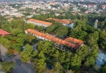 Jammu and Kashmir: 60 Schools in Kashmir Valley to Suspend Classwork for NEET Re-Test Aerial shot showcasing a city landscape with a prominent school building amidst green trees.
