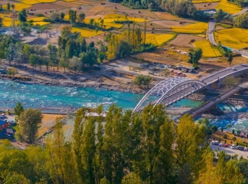 Aerial view of a picturesque bridge crossing a turquoise river in the rural fields of Ganderbal.