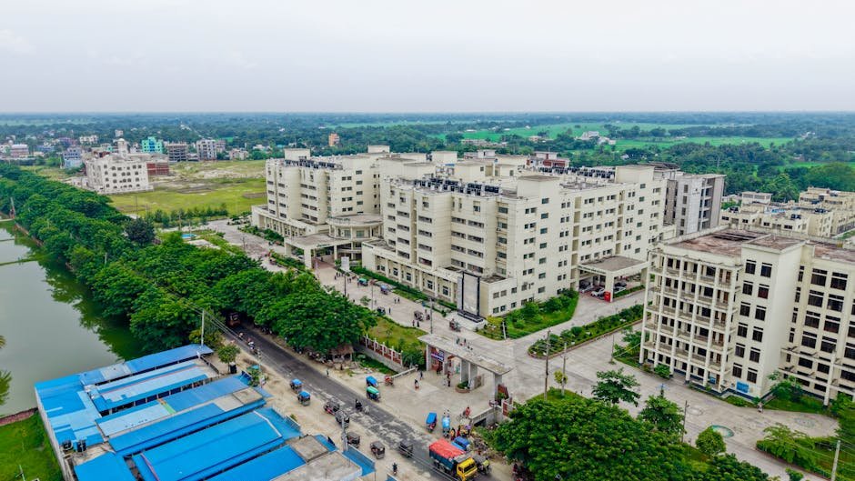 Jammu and Kashmir: Over Half of Posts Vacant at SKIMS Soura, Crippling Healthcare Aerial view of the Kushtia Medical College campus showing modern architecture and lush surroundings.