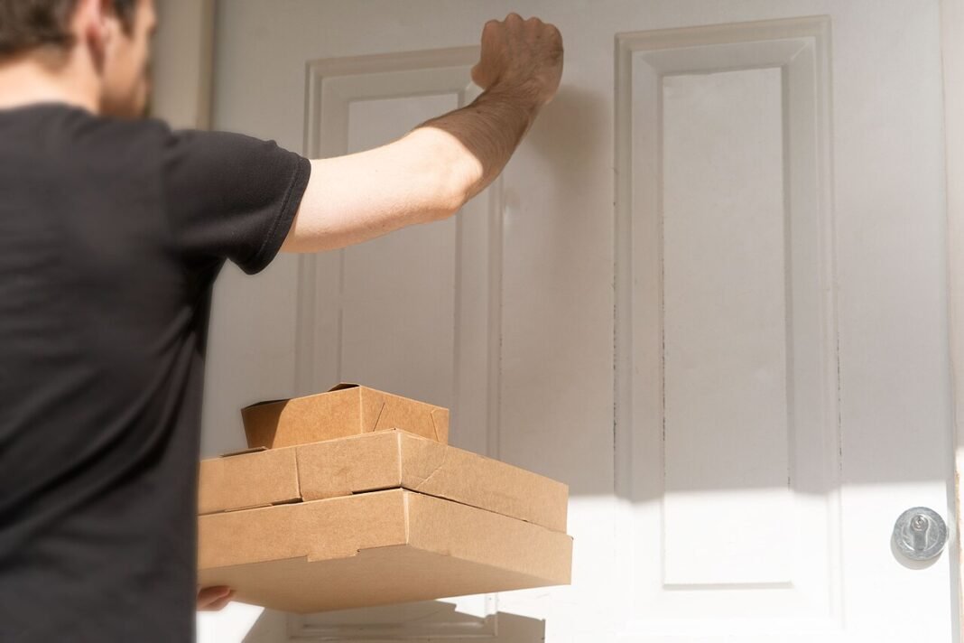 Middle East Conflict’s Ripple Effect: The Hidden Costs of Food Delivery Packaging An image of a delivery driver knocking on a white front door to deliver three cardboard takeaway boxes. This image is free to use under the Creative Commons Attribution Licence. Feel free to use it w…