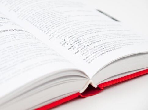 An open book with a red cover showing pages filled with text, symbolizing knowledge and education. An open book with a red cover showing pages filled with text, symbolizing knowledge and education.