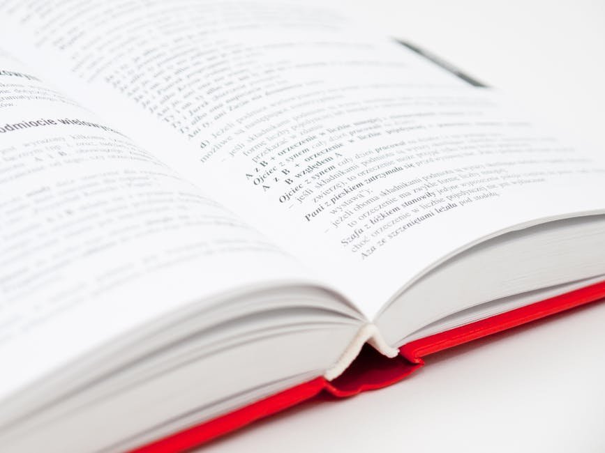 An open book with a red cover showing pages filled with text, symbolizing knowledge and education.