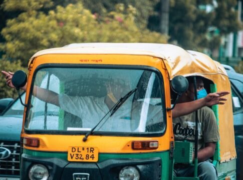 Auto rickshaw navigating the rainy streets of Delhi with passengers gesturing directions.