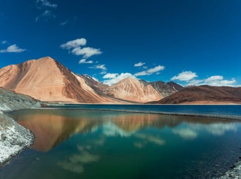 Beautiful panorama of Pangong Lake with majestic Himalayan mountains under a clear blue sky.