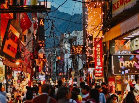 Bustling evening street market in Katra, India with colorful lights and crowds.