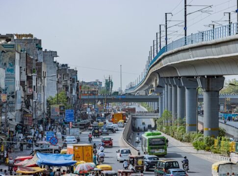 Busy street scene in Delhi with elevated metro and urban traffic capturing vibrant city life.