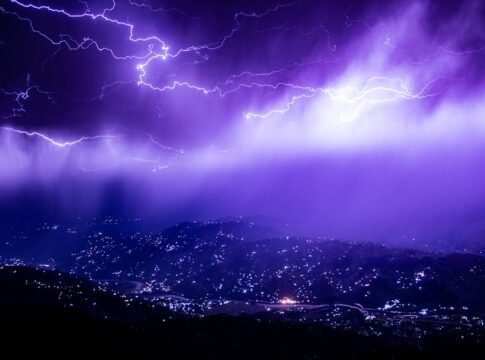 Captivating lightning storm over Muzaffarabad with a vivid purple sky, lighting up the mountains at night.