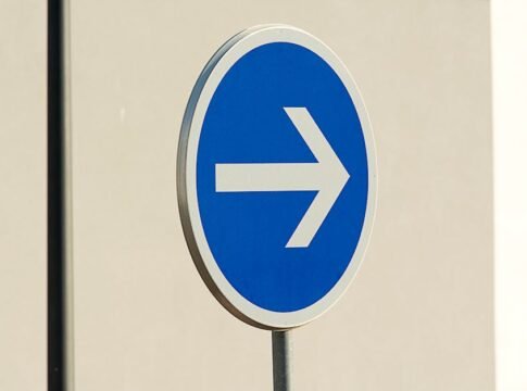 Close-up of a blue directional arrow traffic sign against a neutral background. Close-up of a blue directional arrow traffic sign against a neutral background.