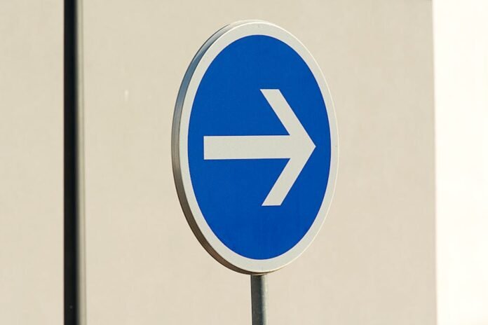 Close-up of a blue directional arrow traffic sign against a neutral background. Close-up of a blue directional arrow traffic sign against a neutral background.