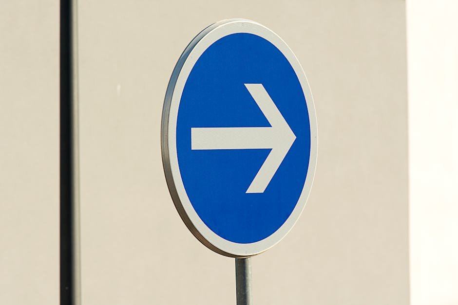 Close-up of a blue directional arrow traffic sign against a neutral background. Close-up of a blue directional arrow traffic sign against a neutral background.