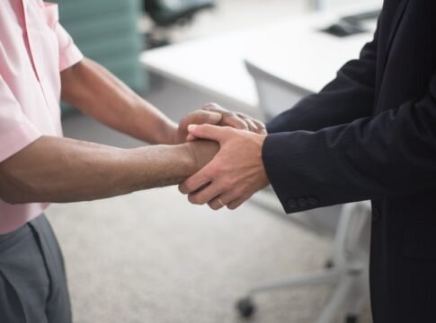 Close-up of a formal handshake between two businessmen in an office environment.