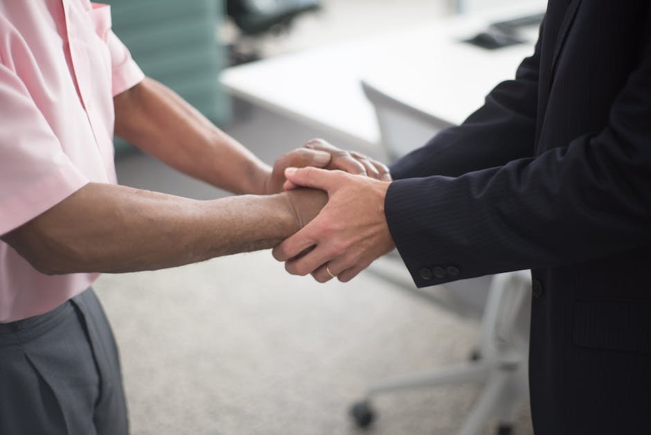 Close-up of a formal handshake between two businessmen in an office environment.