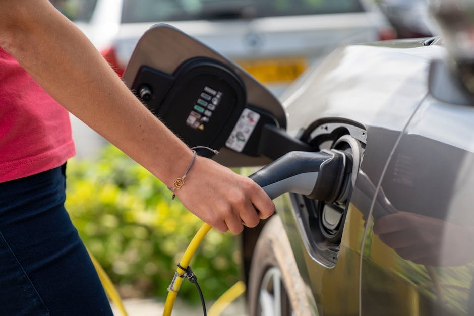 Delhi Unveils Draft EV Policy 2026-2030 with Significant Tax Breaks and Incentives Close-up of a person plugging in an electric car at a charging station outdoors.