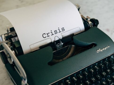 Close-up of a vintage typewriter with the word 'Crisis' typed on paper.