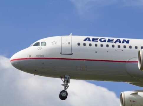 Close-up view of an Aegean Airlines Airbus A321 plane in flight against a bright sky.
