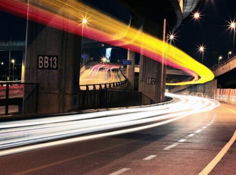 Dynamic urban scene at night showcasing colorful light trails on an expressway.