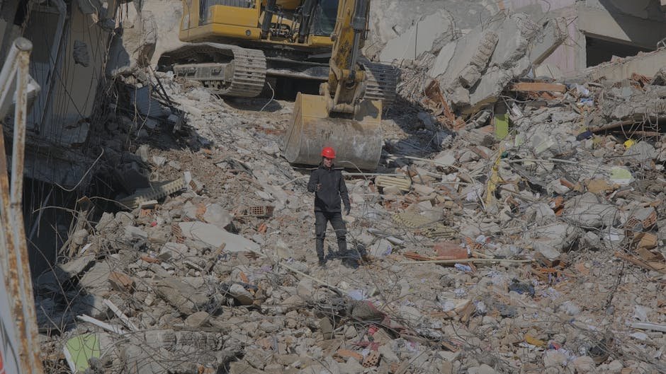 Mumbai Authorities Demolish Over 1,400 Shanties in Mankhurd, Render Hundreds Homeless Excavator clearing urban demolition site rubble with a worker on site.