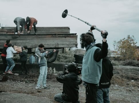 Film crew working outdoors, capturing scenes with camera and boom mic. Film crew working outdoors, capturing scenes with camera and boom mic.