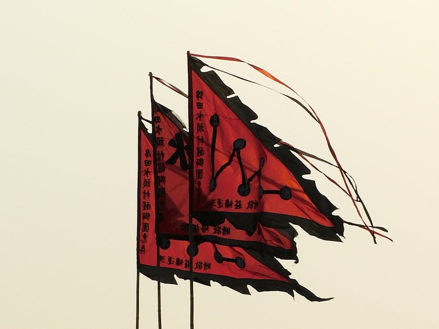 From below of similar red and black flags with hieroglyphs waving in wind against cloudy sky