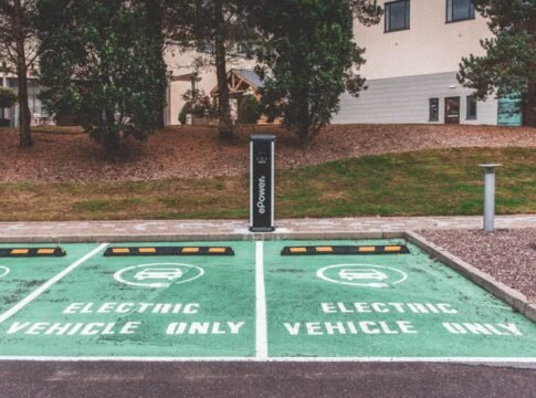Green electric vehicle parking with charging station in urban environment.