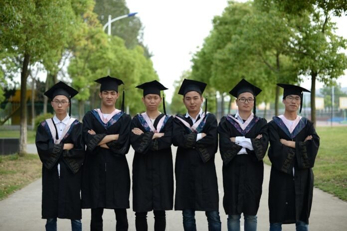 Group of young graduates in gowns and caps standing outdoors, celebrating academic achievement. Group of young graduates in gowns and caps standing outdoors, celebrating academic achievement.