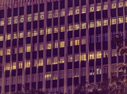Illuminated urban office building facade at night in New Delhi, showcasing modern architecture with glowing windows.