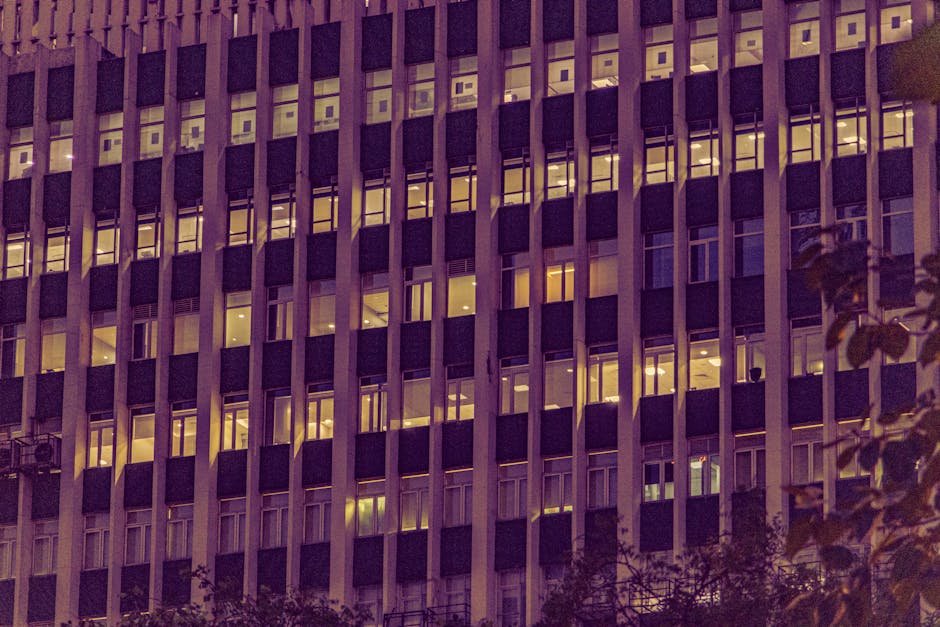 Illuminated urban office building facade at night in New Delhi, showcasing modern architecture with glowing windows.