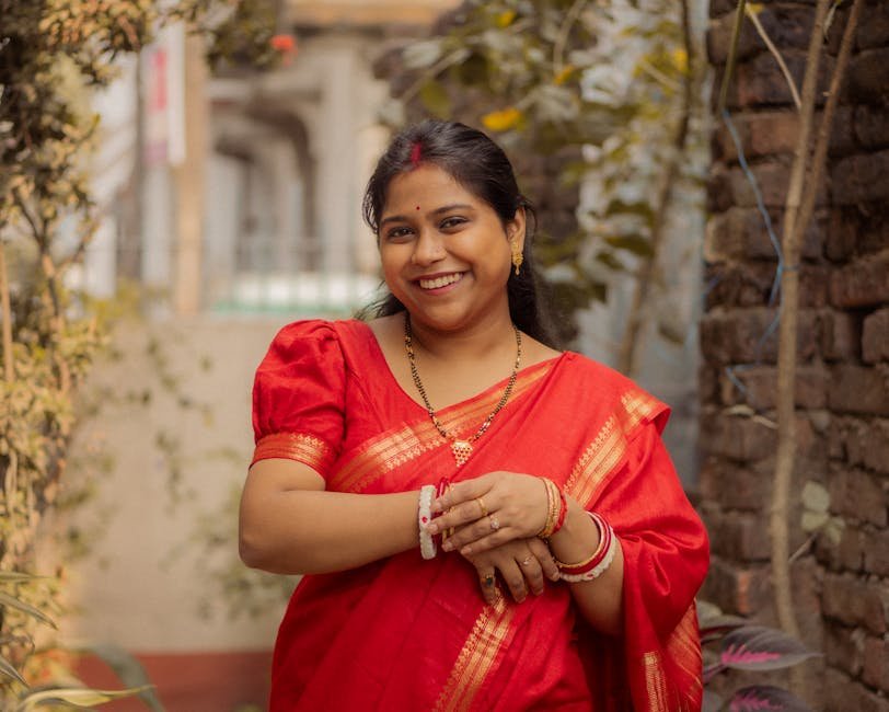 Mumbai Civic Chief to Prioritize Monthly Departmental Reviews to Enhance Efficiency Joyful woman in a vibrant red sari posing outdoors with a natural background, showcasing cultural attire.